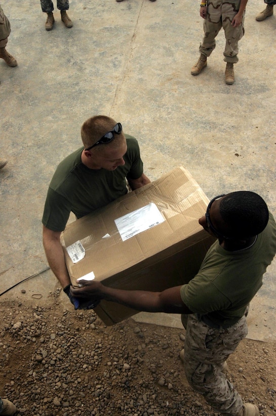 Corporal Leonard B. Huebner (left), a 21-year-old native of Buchanan, Mich., and motor transportation mechanic and Pfc. Brandon A. Hill, a 19-year-old native of Aberdeen, Md., and postal clerk unload a care package from a shipment of mail destined for a service member based in Ramadi.
