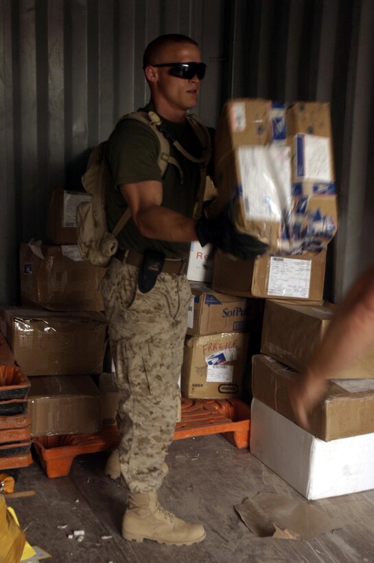 Sergeant Addam C. Baker, a 26-year-old native of Witchita, Kan., and postal chief here unloads a care package from a shipment of mail destined for a service member based in Ramadi.