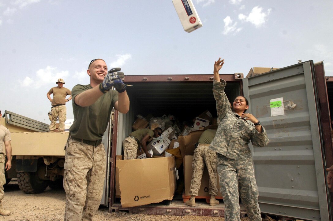Corporal Leonard B. Huebner (left), a 21-year-old native of Buchanan, Mich., and motor transportation mechanic and Spc. Sandra S. Cardenas, a 25-year-old native of Exeter, Penn., and finance specialist help unload a shipment of mail destined for service members based throughout Ramadi.