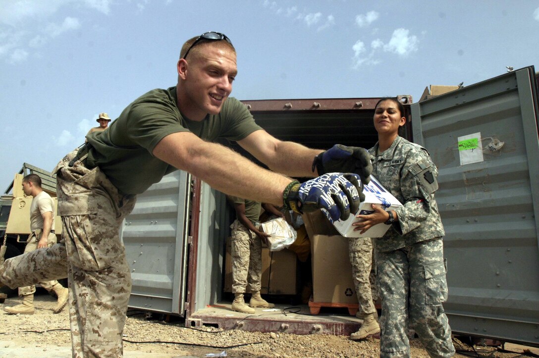 Corporal Leonard B. Huebner (left), a 21-year-old native of Buchanan, Mich., and motor transportation mechanic and Spc. Sandra S. Cardenas, a 25-year-old native of Exeter, Penn., and finance specialist help unload a shipment of mail destined for service members based throughout Ramadi.