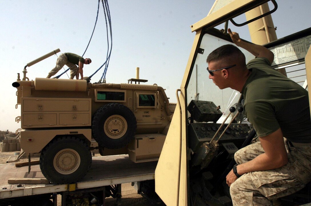 Lance Cpl. Paul M. Moore a 21-year-old Perryville, Mo. native and motor transportation operator hooks cables to a vehicle while Cpl. Andrew Breen, a 21-year-old Oracle, Ariz. native and heavy equipment operator looks on. Both Marines are assigned to Task Force Roadrunner here.