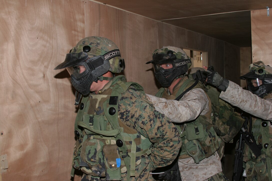 Lance Cpl. Michael E. Fuller, light armored vehicle gunner with Charlie Company, 3rd Light Armored Reconnaissance Battalion, and a 21-year-old Brenham, Texas, native role plays an insurgent and is apprehended by infantry scouts Lance Cpl. Jesse R. Walden, a 20-year-old Miuskogee, Okla., native, (center) and Cpl. Joel P. Noland, a 21-year-old Schaumburg, Ill., native during a cordon-and-knock operation inside the military operations on urban terrain town at the Combat Center?s Range 200 Oct. 18.