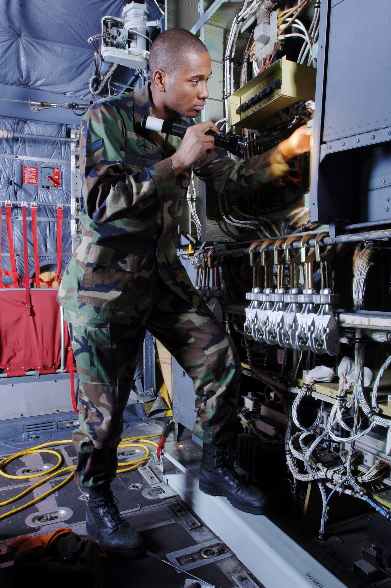 YOKOTA AIR BASE, Japan -- Airman 1st Class Marlon Wells uses a flashlight to visually inspect the avionics system in the cargo bay of a C-130 Hercules aircraft here. Airman Wells is looking for chaffed, frayed and disconnected wires to prevent system failure. He is a C-130 crew chief from the 374th Maintenance Squadron/ isochronal section, here at Yokota Air Base, Japan. (U.S. Air Force photo by Master Sgt Val Gempis)