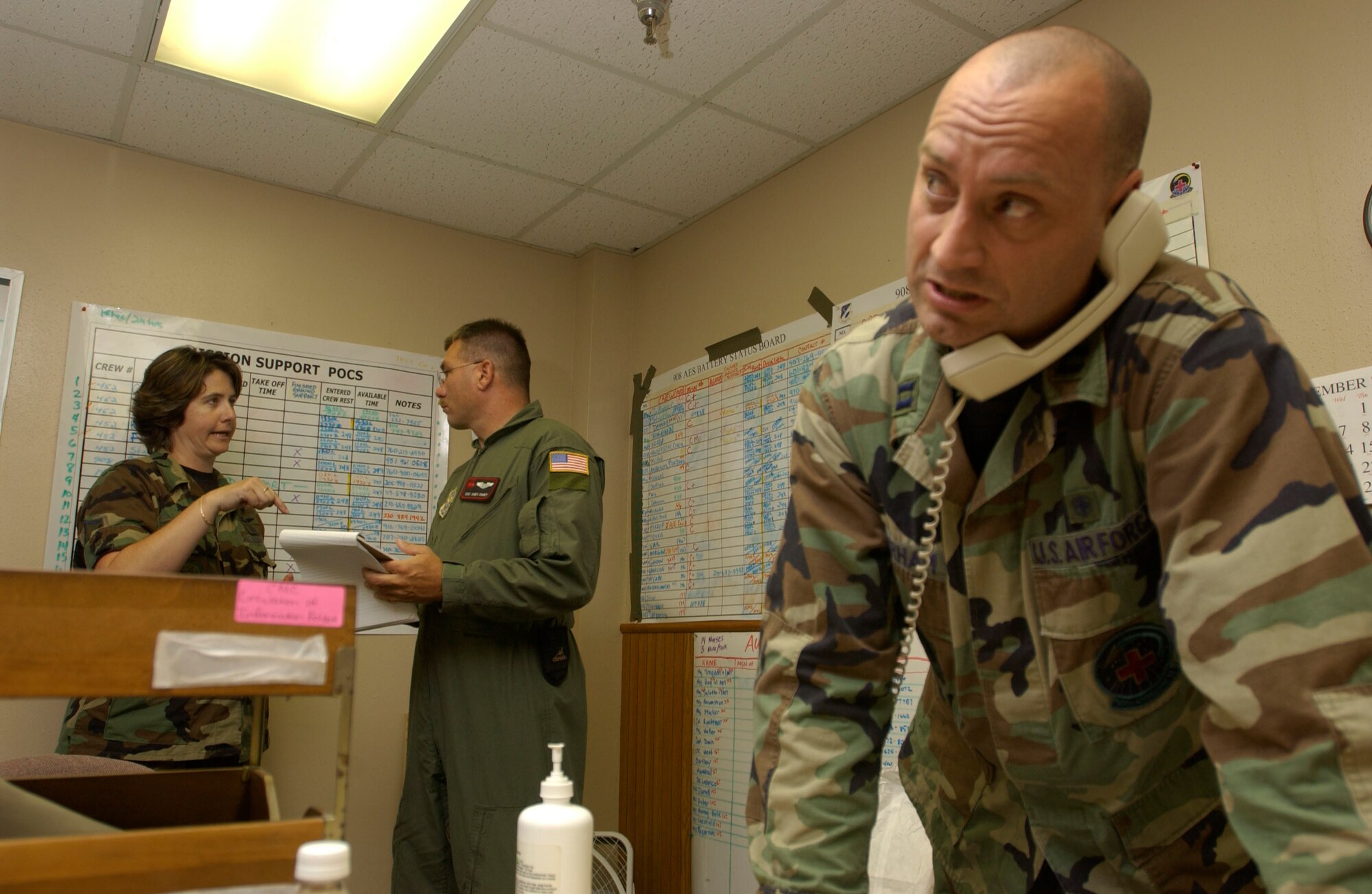 050905-F-7441-2403   Master Sgt. Julianna Simmons discusses crew arrangements with Staff Sgt. James Chaney as Capt. Jameson Durham talks on the phone. All three reservists worked with a handful of others to coordinate aeromedical evacuation missions for Hurricane Katrina relief at Kelly Field, Texas. (U.S. Air Force photo by Tech. Sgt. Jason Tudor)                               