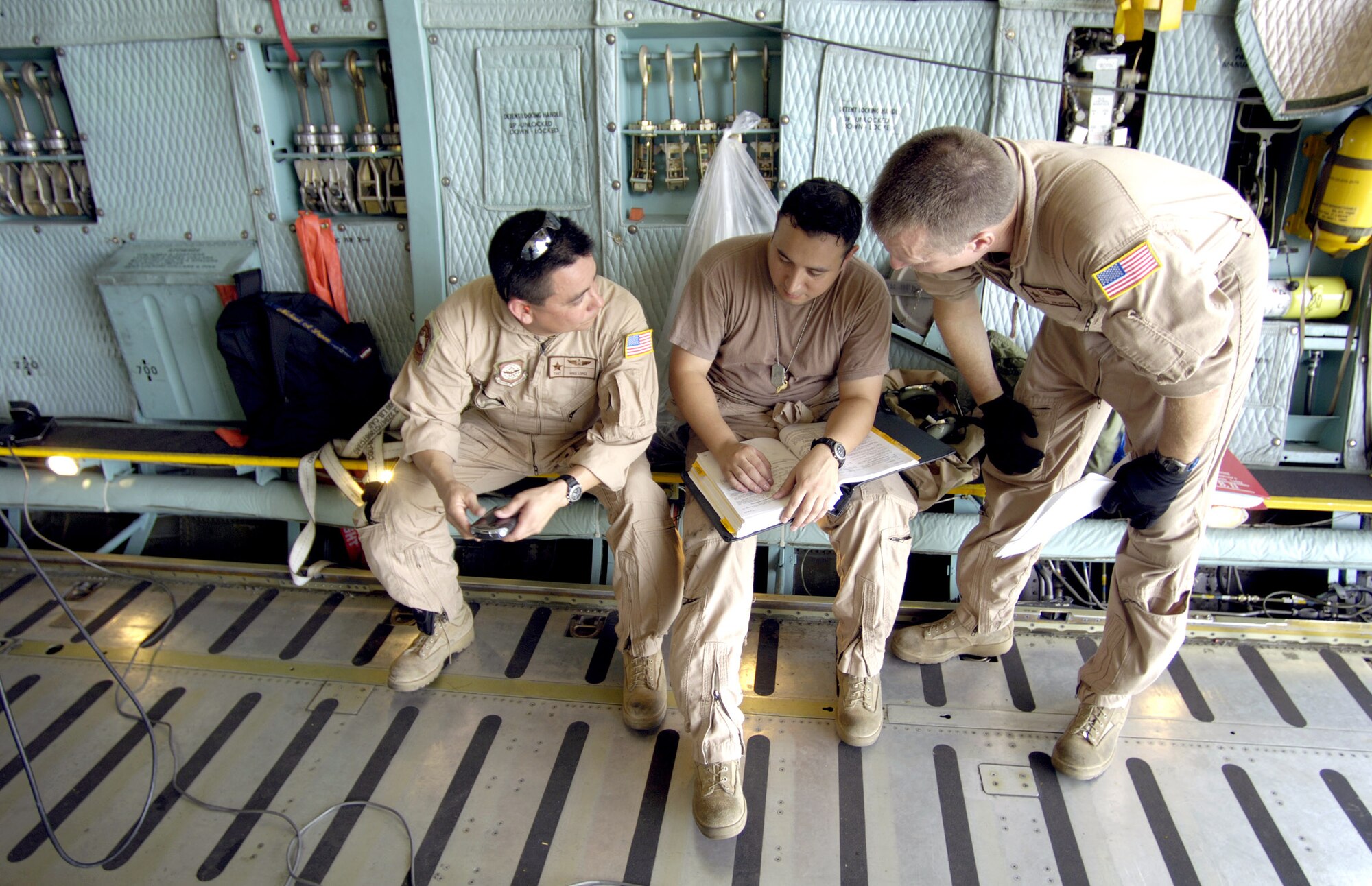 HICKAM AIR FORCE BASE, Hawaii -- Loadmasters Tech. Sgt. Mike Lopez, Senior Airman Marcial Cadena and Staff Sgt. Joe Nicholes, check a technical order before loading a CH-47 Chinook heavy lift helicopter onto their C-5 Galaxy here. The Airmen from the Air Force Reserve 433rd Airlift Wing, Lackland Air Force Base, Texas, helped ferry 60 troops, four helicopters and support equipment to Pakistan to support earthquake relief operations Oct. 16. The Soldiers are from Company B, 214th Aviation Regiment of the 2nd Battalion, 25th Aviation Regiment at nearby Wheeler Army Air Field. (U.S. Air Force photo by Tech. Sgt. Shane A. Cuomo)