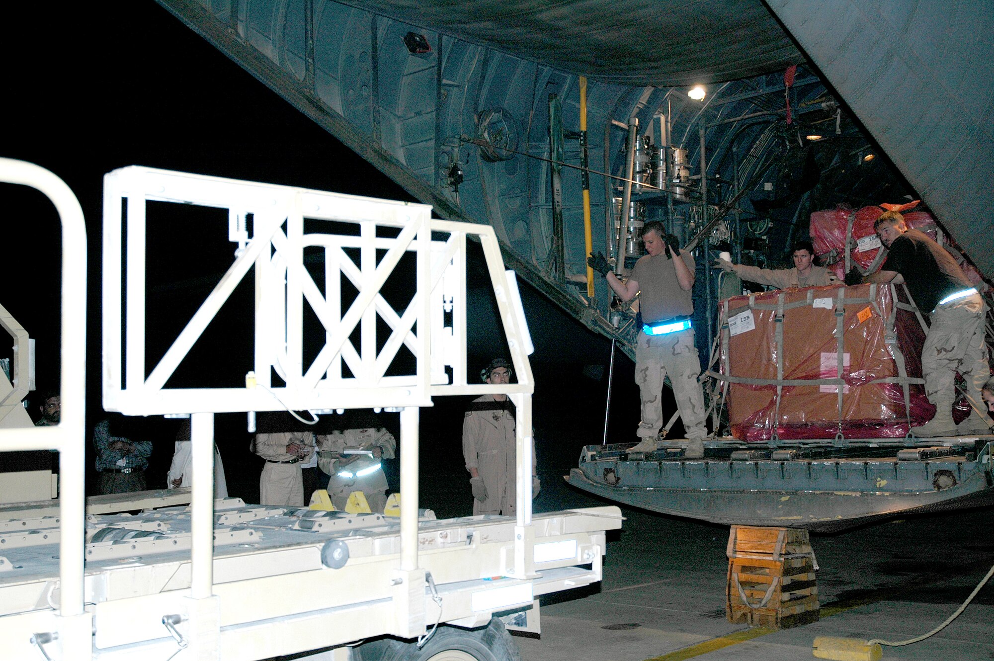 CHAKLALA, Pakistan -- Airmen here transport supplies from a C-130 Hercules to a hangar. The hangar is used to store the tons of relief supplies arriving here to aid the survivors of the massive Oct. 8 earthquake. (U.S. Air Force photo by Senior Airman Cassandra Locke)