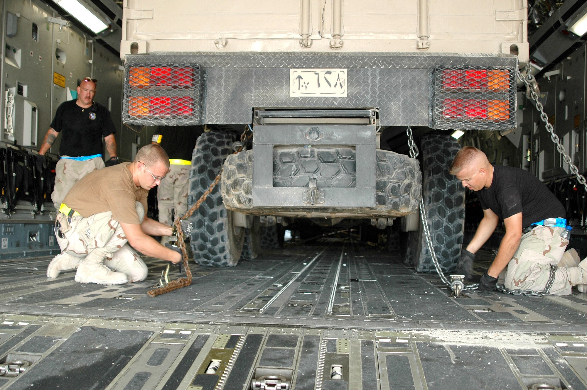 SOUTHWEST ASIA -- Airman 1st Class Ryan Pappas (left foreground) and Senior Airman James Depew secure Qatari earthquake relief equipment bound for Pakistan to the cargo deck of C-17 Globemaster III. Staff Sgt. Ken Schoen observes the procedures. The Airmen are part of the 8th Expeditionary Air Mobility Squadron. (U.S. Air Force photo by Master Sgt. Peter Borys)