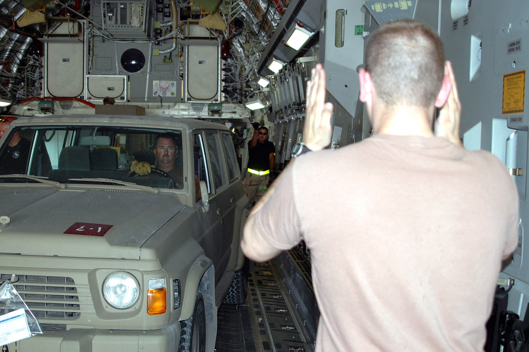 SOUTHWEST ASIA -- Staff Sgt. Ramone Herrera marshals a Qatari vehicle driven by Tech. Sgt. Jeffrey Brown while another Airman spots for them as they drive onto a C-17 Globemaster III aircraft. The vehicle is part of the earthquake relief aid Qatar sent to Pakistan. The Airmen are part of the 8th Expeditionary Air Mobility Squadron. (U.S. Air Force photo by Master Sgt. Peter Borys)
