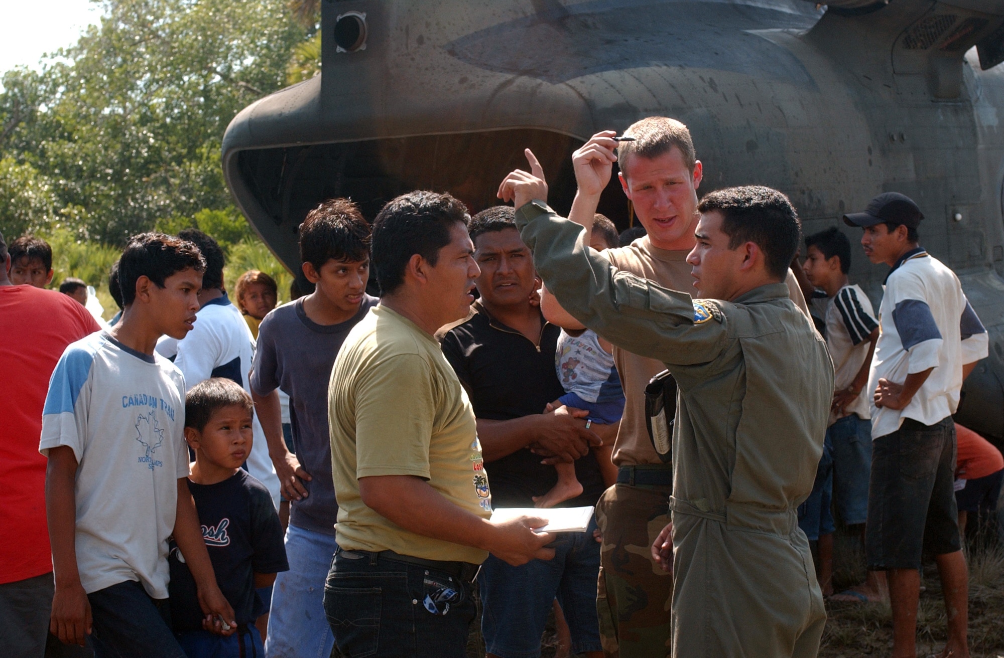 GUATEMALA -- Army 1st Lt. Matthew Tunison (front, right) works with a translator from the Guatemalan Air Force to get an assesment of road conditions into the village of Ocos, Guatemala, after airlifting a shipment of food, water and medicine. The area was devastated by the effects of Hurricane Stan. Members of the 1st Battalion, 228th Aviation Regiment and Joint Task Force-Bravo arrived here Oct. 7 to help airlift relief supplies to those affected by the hurricane. Lieutenant Tunison is a helicopter pilot with the 1-228th AR. (U.S. Air Force photo by Tech. Sgt. Mike Edwards)                               