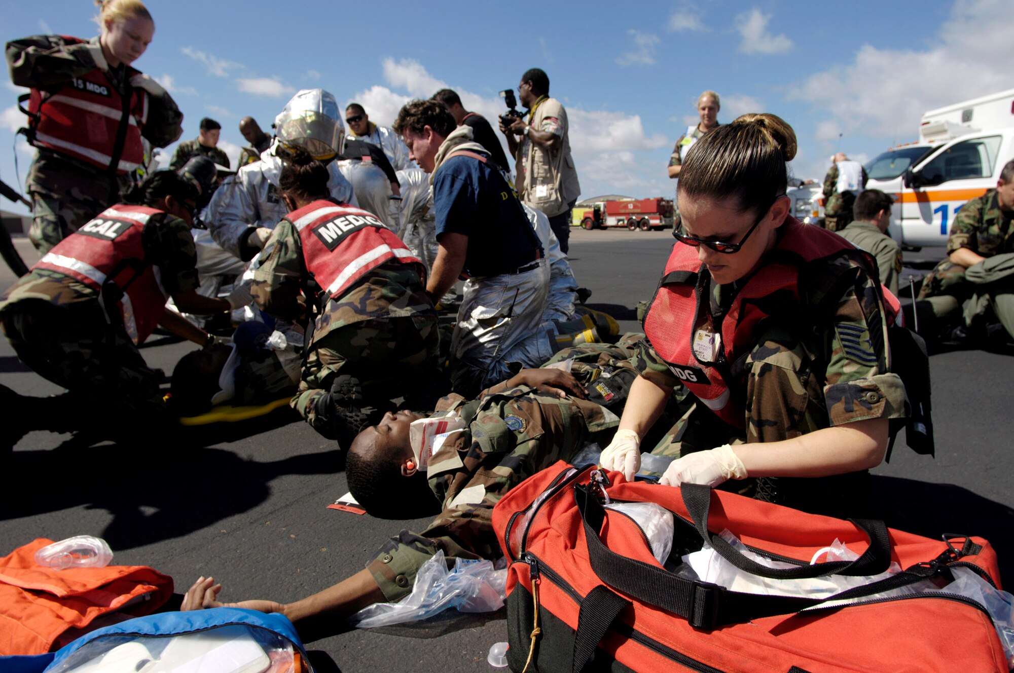 HICKAM AIR FORCE BASE, Hawaii -- Airmen from the 15th Airlift Wing fire department and medical group treat simulated wounded patients during an initial response readiness exercise here. The exercise, held Oct. 17, marks the first time the base used an actual C-130 Hercules and aircrew to increase the training's realism. The wing's search and rescue team also took part, entering the aircraft -- from the Hawaii Air National Guard's 154th Wing -- to retrieve and process "bodies." The exercise also tested the interaction between the two wings. (U.S. Air Force photo by Tech. Sgt. Shane A. Cuomo)