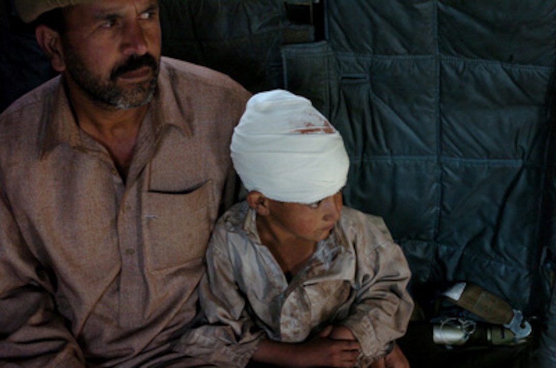 A Pakistani father sits with his son aboard a U.S. Navy MH-53 Sea Dragon helicopter while being evacuated to Islamabad, Pakistan, for medical treatment on Oct. 17, 2005. The Department of Defense is participating in the multinational effort to provide humanitarian assistance and support to Pakistan and parts of India and Afghanistan following a devastating earthquake. 