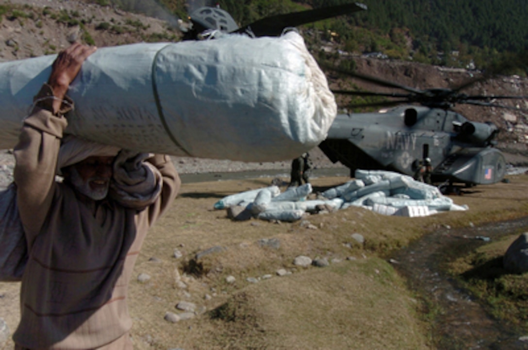 An elderly Pakistani man carries a tent away from a U.S. Navy MH-53 Sea Dragon helicopter in Balikot, Pakistan, on Oct. 19, 2005. The Department of Defense is participating in the multinational effort to provide humanitarian assistance and support to Pakistan and parts of India and Afghanistan following a devastating earthquake. The Sea Dragon is attached to Helicopter Mine Countermeasures Squadron 15 of Naval Air Station, Norfolk, Va. 