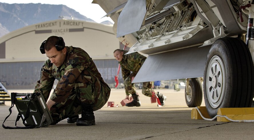 Staff Sgt. Jason McDonald (left), a weapons load crew chief, checks his technical orders after loading two joint direct attack munitions onto an F/A-22 Raptor. The sergeant and the Raptors, from the 27th Fighter Squadron at Langley Air Force Base, Va., deployed to Hill AFB, Utah, to take part in exercise Combat Hammer. (Air Force photo by Staff Sgt. Samuel Rogers)
