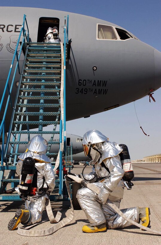 SOUTHWEST ASIA -- Senior Airman Tony Brown and Staff Sgt. Kevan Moniz feed a fire hose up the ladder into a KC-10 aircraft during a response exercise at this desert air base. Airman Brown is deployed here from the 309th Airlift Squadron at Chievres, Belgium. Sergeant Moniz is from the 775th Civil Engineering Squadron at Hill AFB, Utah. (U.S. Air Force photo by Joey Shumate)