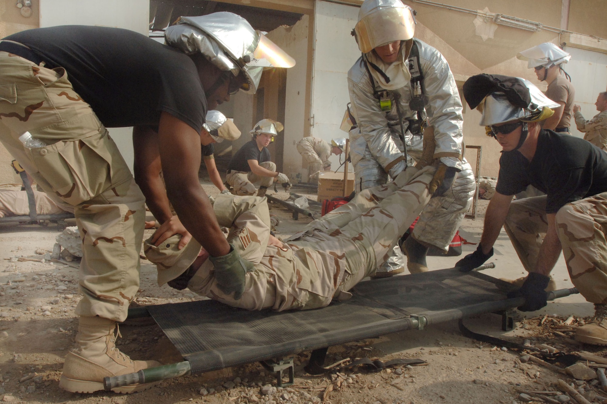 ALI BASE, Iraq -- Senior Airman Donnie Rogers (left), Airman Micheal Delong (center) and Airman 1st Class Robert Jacobs put a mock patient on a stretcher during  a mass casualty fire alert exercise here. The Airmen are deployed here to the 407th Expeditionary Civil Engineer Squadron fire department. Airman Rogers is from the 4th Civil Engineers Squadron at Seymour Johnson Air Force Base, N.C.; Airman Delong from the 28th CES at Ellsworth AFB, S.D.; and Airman Jacobs from the 60th CES at Travis AFB, Calif. The training exercise, which simulated a mass casualty fire alert, will help prepare firefighters here for real-world events. (U.S. Air Force photo by Senior Airman Jennifer Haas) 