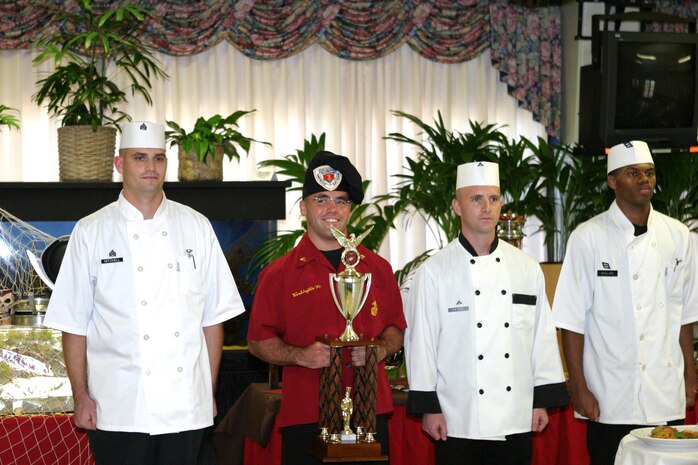 Cpl. David Washington Jr., 3rd Battalion, 3rd Marine Regiment, smiles as he holds the trophy he received after winning the Chef of the Quarter competition, Oct. 21, at Anderson Hall. Other cooks competing  were Sgt. William Mitchell (left), Lance Cpl. Christopher Perna, and Seaman Harold Wallace.