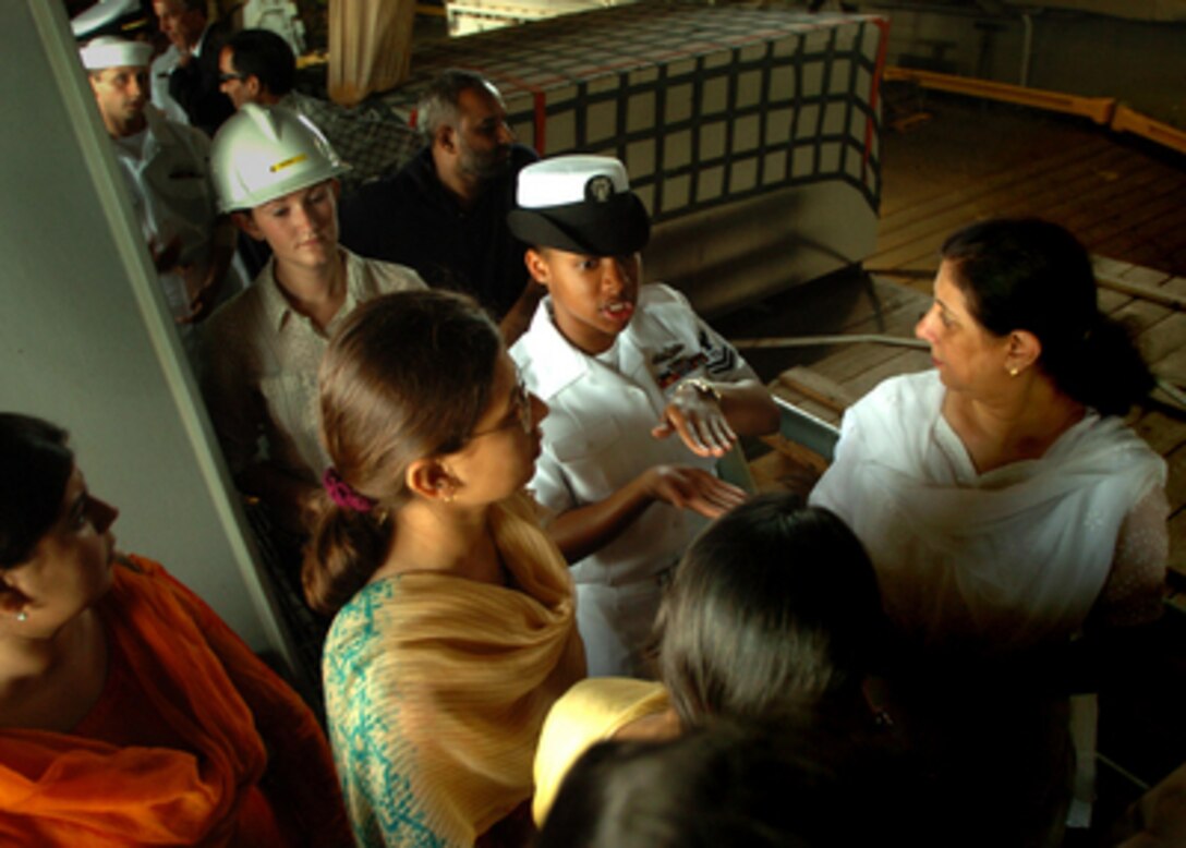 U.S. Navy Petty Officer 2nd Class Tomika Harris (center) explains well deck operations to a group of Pakistani women on a tour of the USS Pearl Harbor (LSD 52) in Karachi, Pakistan, on Oct. 24, 2005. The dock landing ship is in Karachi to unload 140 tons of disaster relief supplies for Pakistan. The Department of Defense is delivering disaster relief supplies and services as part of a multinational effort to provide aid and support to Pakistan and parts of India and Afghanistan following a devastating earthquake. 