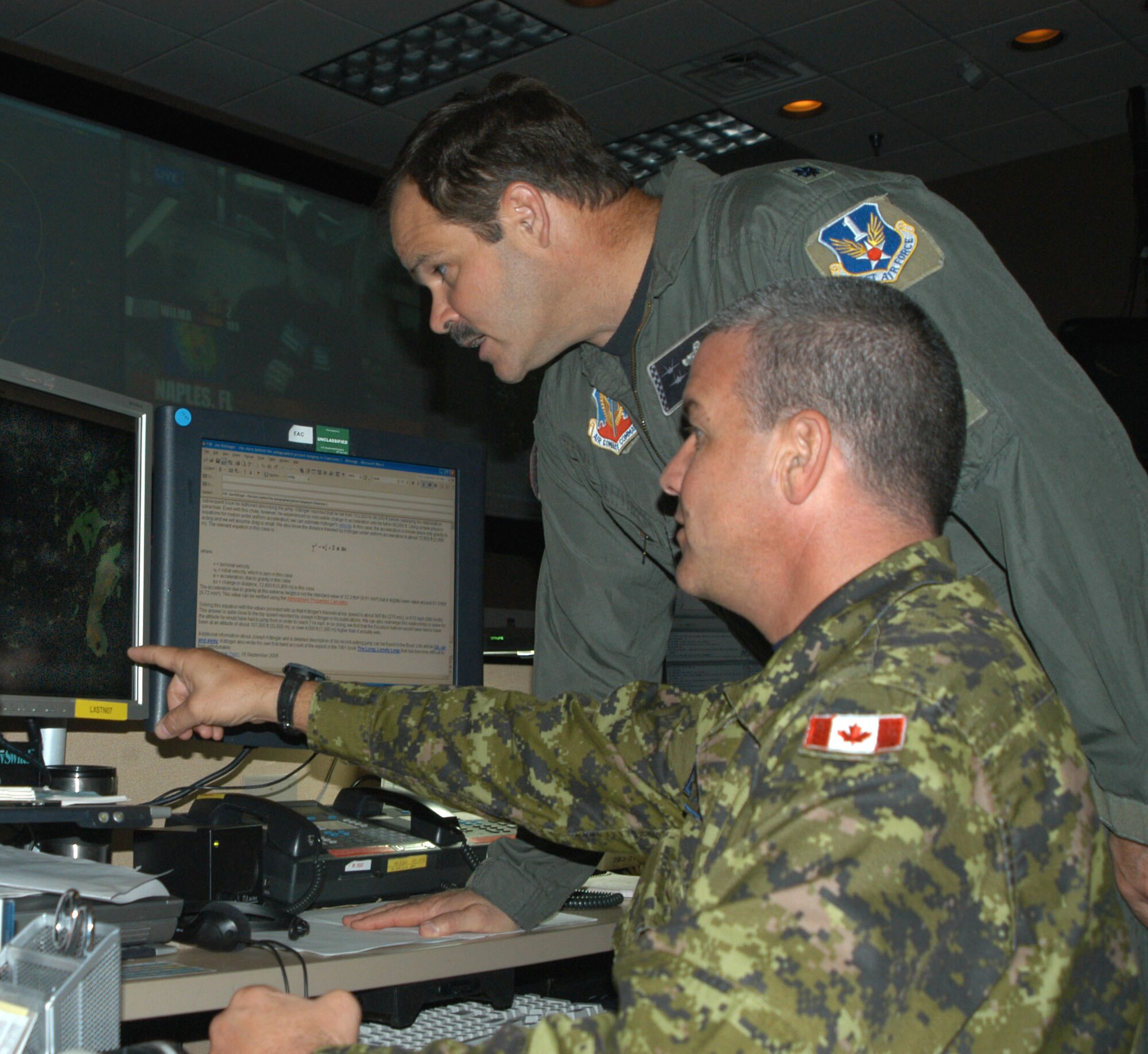 TYNDALL AIR FORCE BASE, Fla. (AFPN) -- Canadian Warrant Officer Richard Nadeau (sitting) and Lt. Col. Steve Browne examine the National Capitol Region air picture. The two are members 1st Air Force, part of North American Air Defense Command here. The command kept an eye on Hurricane Wilma -- and seven others over the past 14 months -- while continuing to protect the nation's skies. (U.S. Air Force photo by Tech. Sgt. Jerry Harlan)                 