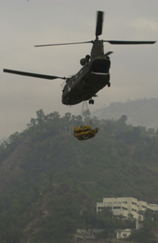 A U.S. Army CH-47D Chinook helicopter sling loads a bulldozer from Muzaffarabad, Pakistan, on Oct. 25, 2005. The Department of Defense is delivering disaster relief supplies and services as part of a multinational effort to provide aid and support to Pakistan and parts of India and Afghanistan following a devastating earthquake. 