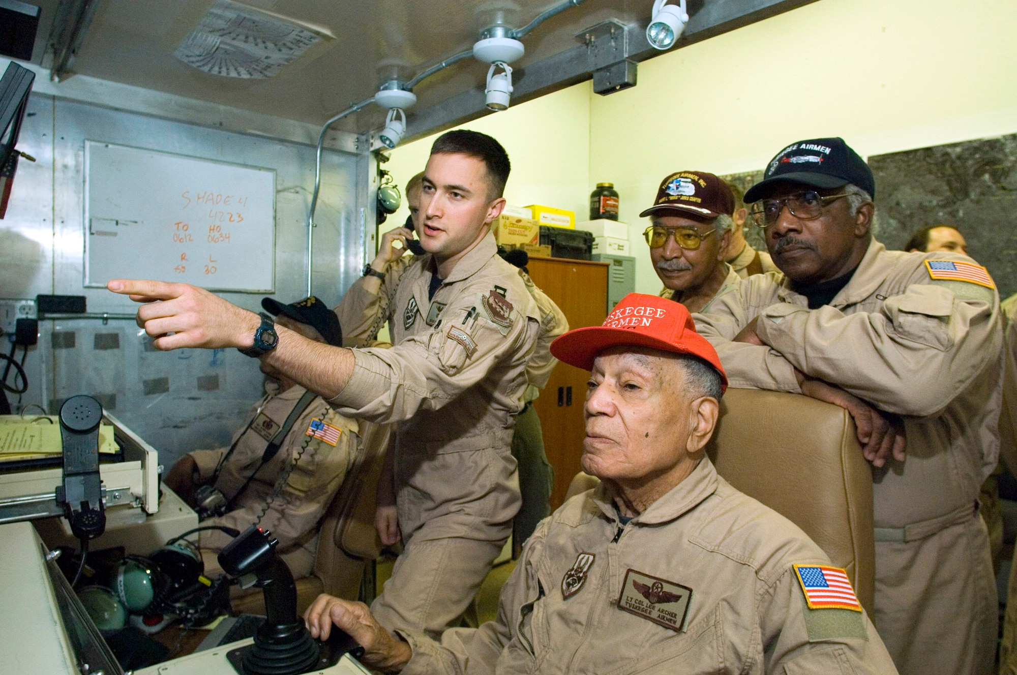BALAD AIR BASE, Iraq (AFPN) -- Capt. Mark Ferstl (left) explains an unmanned aerial vehicle's ground control station to Tuskegee Airmen retired Lt. Col. Lee Archer (sitting) retired Lt. Col Robert Ashby (back right) and retired Col. Dick Toliver (leaning on the chair). The Tuskegee Airmen are here to meet deployed 332nd Expeditionary Operations Group Airmen and observe operations. The Army created the Tuskegee Airmen unit in 1941.  (U.S. Air Force photo by Master Sgt. John E. Lasky)