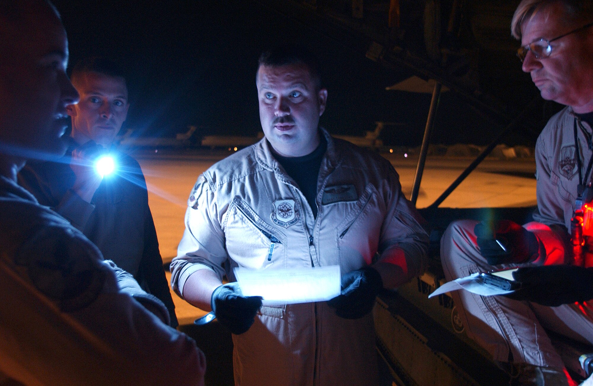 DUSHANBE, Tajikistan -- Staff Sgts. Christopher Yates, center left, and Todd Lowe, center, verify payload information before their C-5 Galaxy departs for Pakistan. The Airmen, from the West Virginia Air National Guard, loaded their cargo plane Oct. 23 with 22,000 pounds of humanitarian goods donated by the people of Tajikistan. The relief aid was bound for earthquake victims in northern Pakistan. (U.S. Air Force photo by Airman 1st Class Dayton Mitchell)