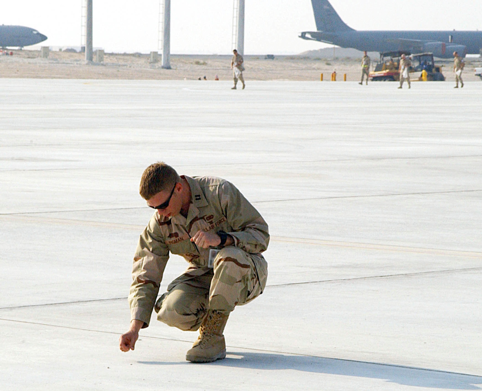 SOUTHWEST ASIA (AFPN) -- Capt. John Pigman finds and removes a piece of debris from the flightline area of this desert air base's new tanker ramp Oct. 22. Captain Pigman was one of more than 200 380th Air Expeditionary Wing volunteers who helped perform this final safety check prior to the official opening of the new ramp. Captain Pigman is a member of the security forces squadron here. (U.S. Air Force photo by Senior Airman Dierra Stokes)