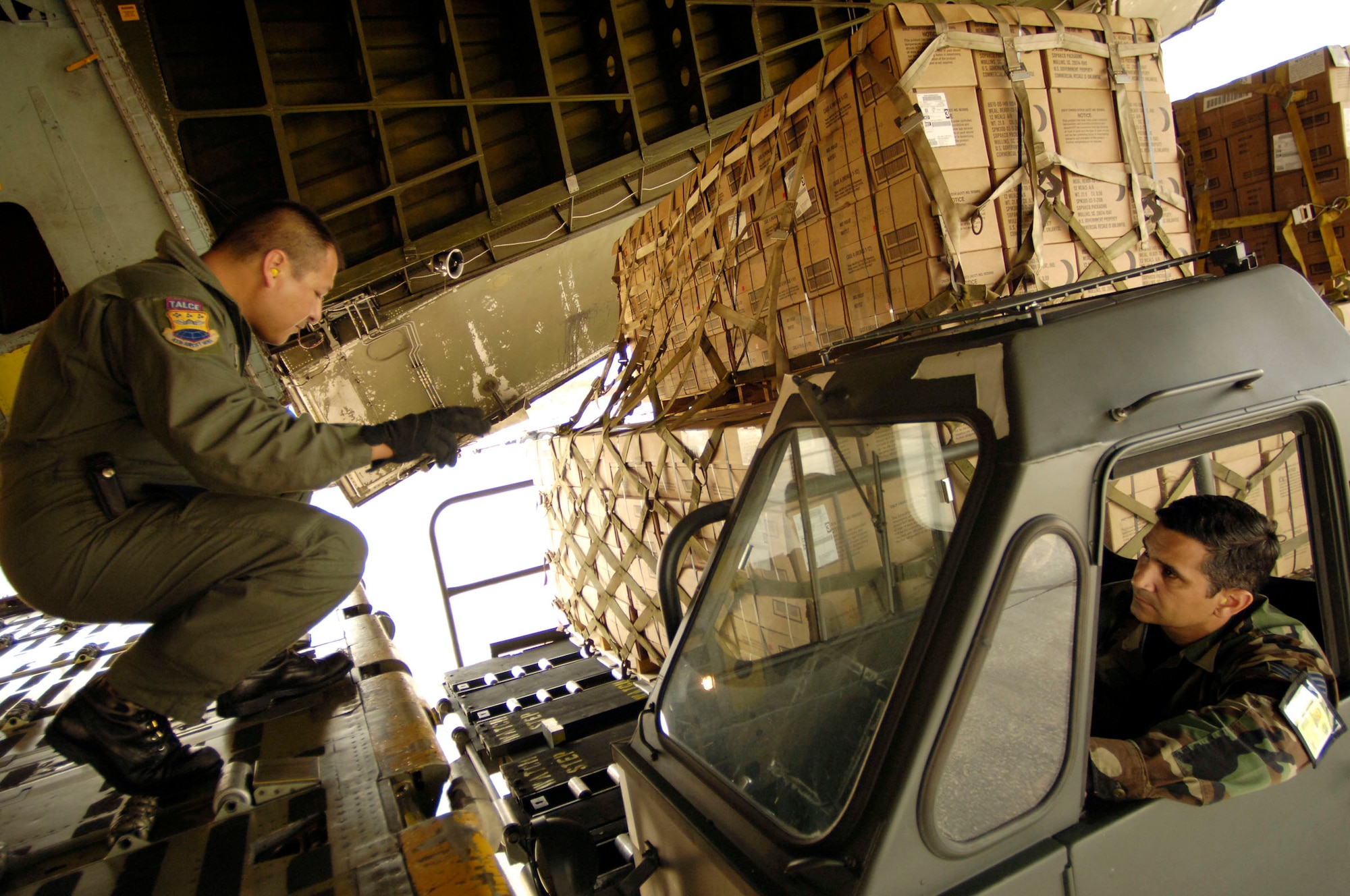 HOMESTEAD AIR RESERVE BASE, Fla. -- Master Sgt. Dave Delgado (left) directs a K-loader operator as he unloads 26,000 pounds of prepackaged meals from a C-5 Galaxy here.  Sergeant Delgado, a loadmaster assigned to the 433rd Airlift Wing, Lackland Air Force Base, Texas, participated in the humanitarian relief effort Oct. 27. (U.S. Air Force photo by Staff Sgt. Jacob N. Bailey) 