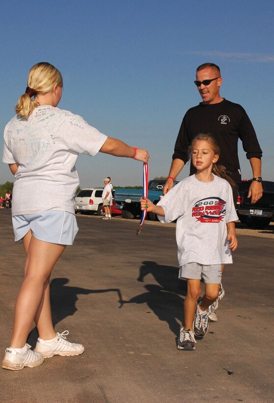 Capt. Brian Bell, Marine Wing Support Squadron 371 Support Company commander, and his daughter Georgia cross the finish line at the 10th-annual Red Ribbon Week walk/run event at West Wetlands Park Oct. 29. Drug Education for Youth kids, Marines, family members and members of the Yuma community gathered for the event to promote drug-free, healthy lifestyles.