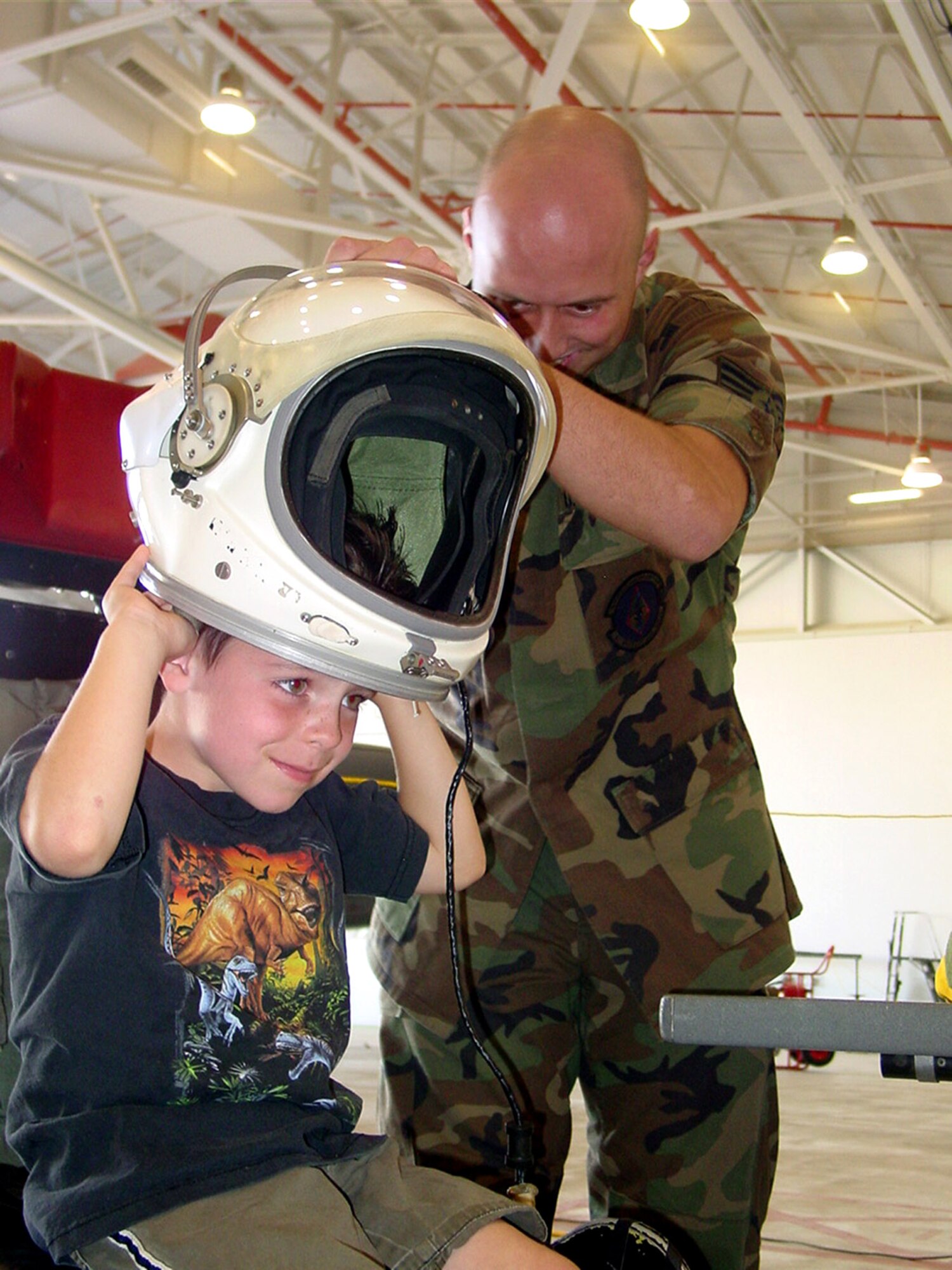 BEALE AIR FORCE BASE, Calif. -- Senior Airman Rocky Howell helps Duncan Ferguson put a helmet on at a full-pressure suit display during military family day here. Airman Howell is assigned to the 9th Physiological Support Squadron. (U.S. Air Force photos by Airman 1st Class Christine Byers)

