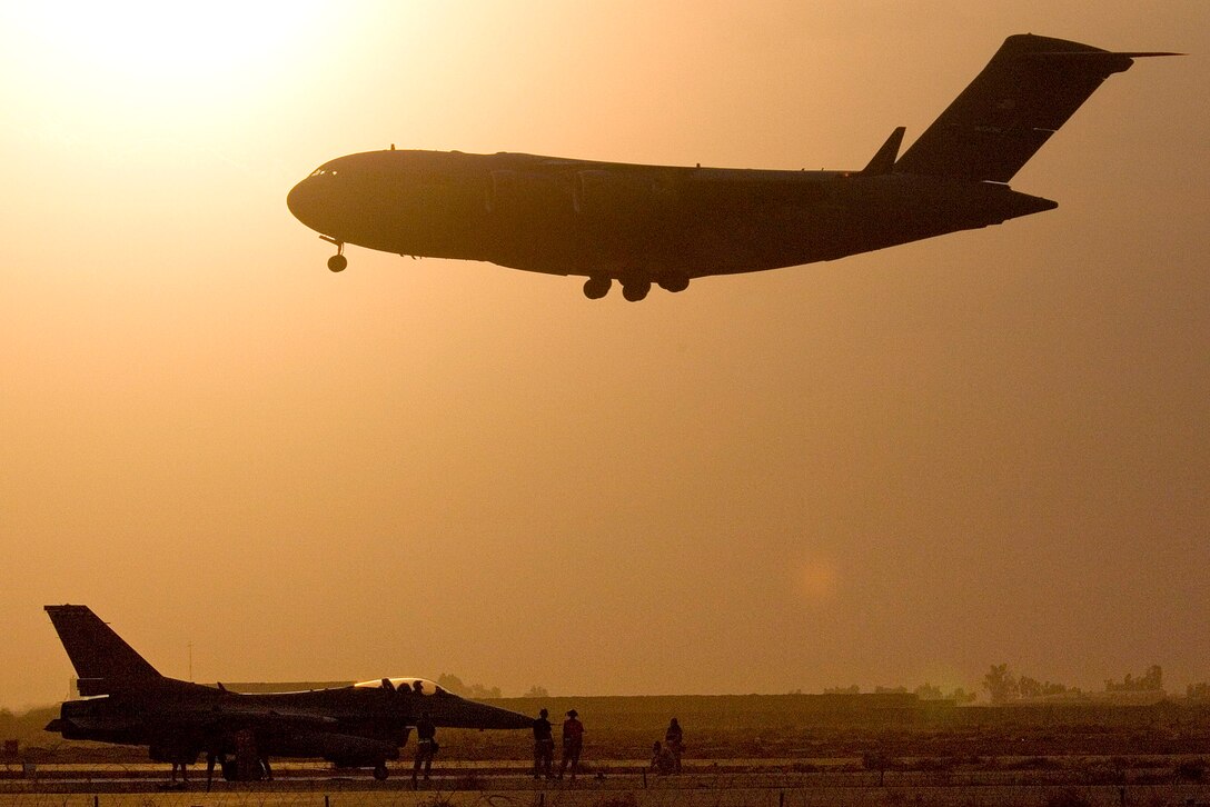 BALAD AIR BASE, Iraq -- A C-17 Globemaster III lands while a F-16 Fighting Falcon is readied for takeoff.  The aircraft and their crews provide air support as needed for the war on terror. (U.S. Air Force photo by Master Sgt. John E. Lasky)