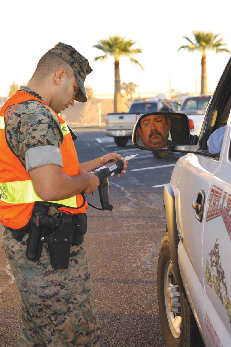 Cpl. Wes Clarke, military policeman, scans the identification card of a civilian contractor Nov. 1 in a drive-through inspection station in the parking lot of Building 852 here. Station MPs, with help from government security agencies, screened all contractors entering the air station?s main gate as part of on-going random anti-terrorism measures.