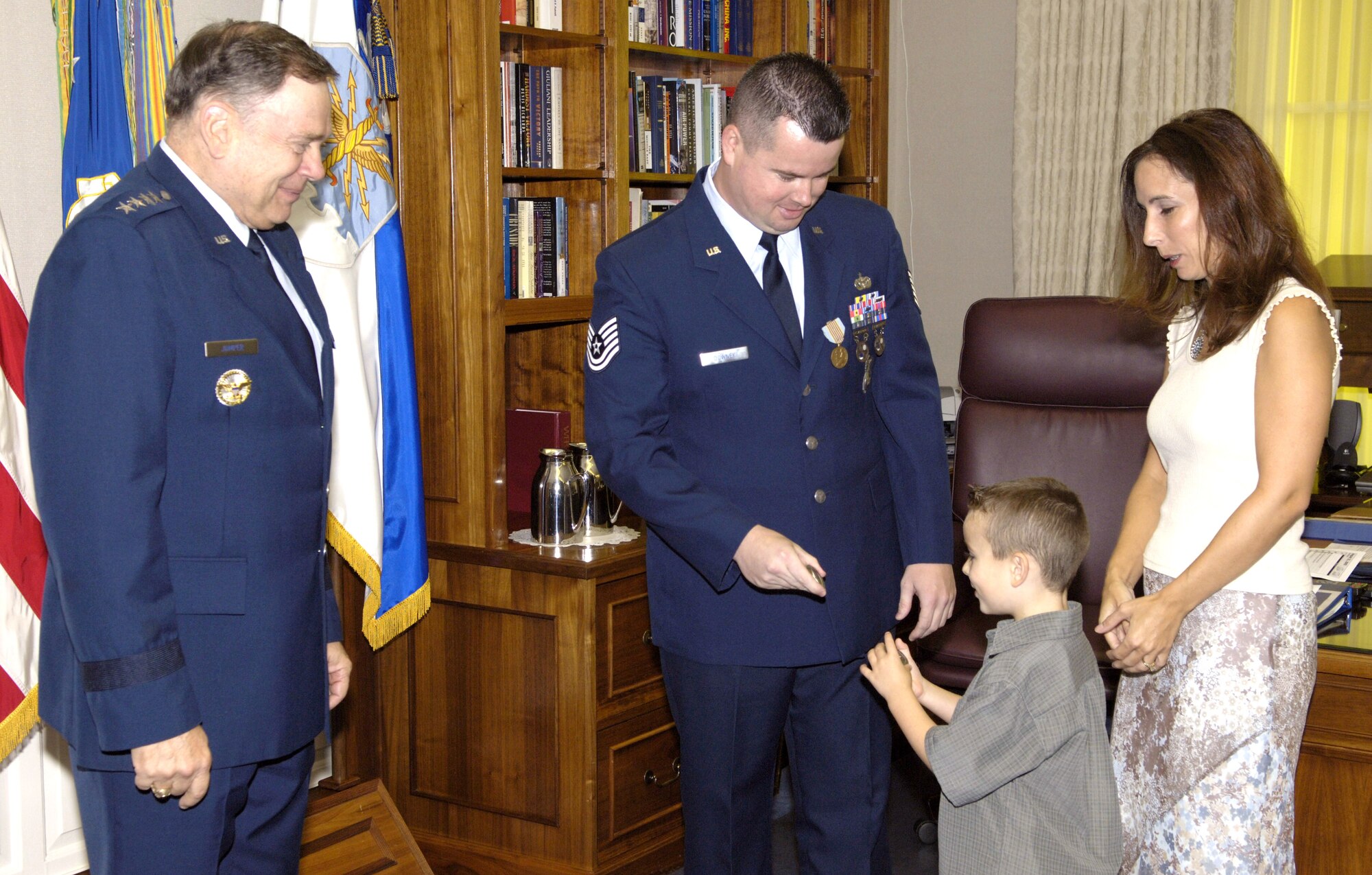 WASHINGTON -- Air Force Chief of Staff Gen. John P. Jumper (left) and Cheryl Downey look on as Tech. Sgt. Michael Downey II and his son, Joseph, compare coins given to them by the chief of staff.  General Jumper presented an Airman's Medal to Sergeant Downy here Aug. 31.  Sergeant Downey was awarded the medal for exemplary courage and heroism on Oct. 17, 2003, when he swam to a vehicle that crashed into a canal and freed an 89-year-old driver who was trapped inside a vehicle.  (U.S. Air Force photo by Master Sgt. Jim Varhegyi)