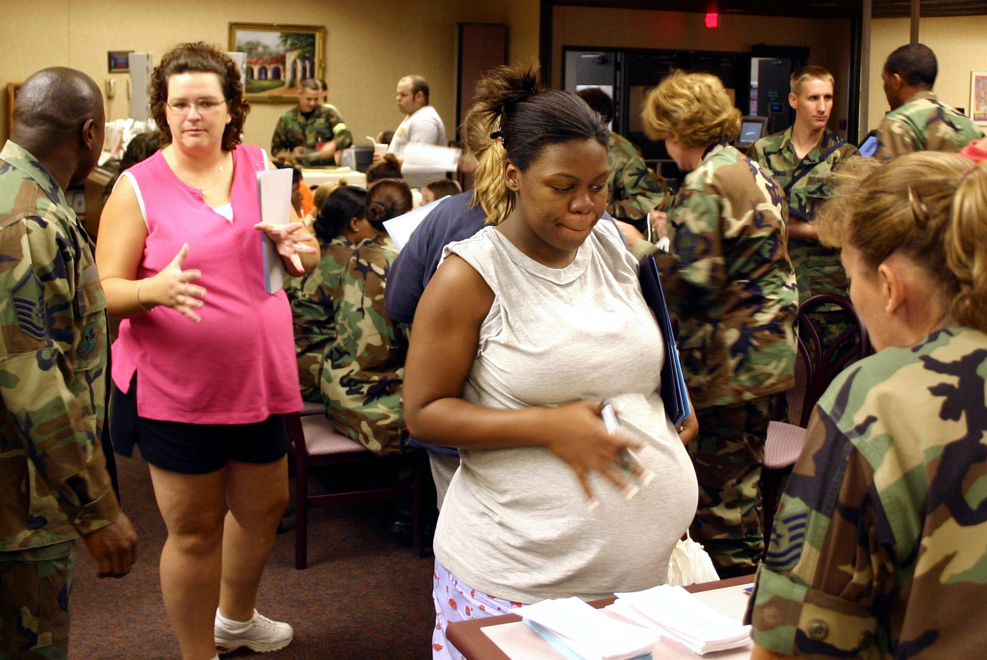 LACKLAND AIR FORCE BASE, Texas -- Senior Airman Kimberly Harris (center) signs in at Wilford Hall Medical Center here after being evacuated from Keesler Air Force Base, Miss., because of Hurricane Katrina on Aug. 30.  Normally, expectant mothers past 36 weeks of pregnancy are recommended not to fly, but because of the conditions at Keesler, 36 expectant mothers, many of them close to their due dates, and their families were flown here to deliver their children. Senior Airman Harris is in her 37th week of pregnancy with her first child and is a vehicle operations specialist from Keesler. (U.S. Air Force photo by Dewey Mitchell)