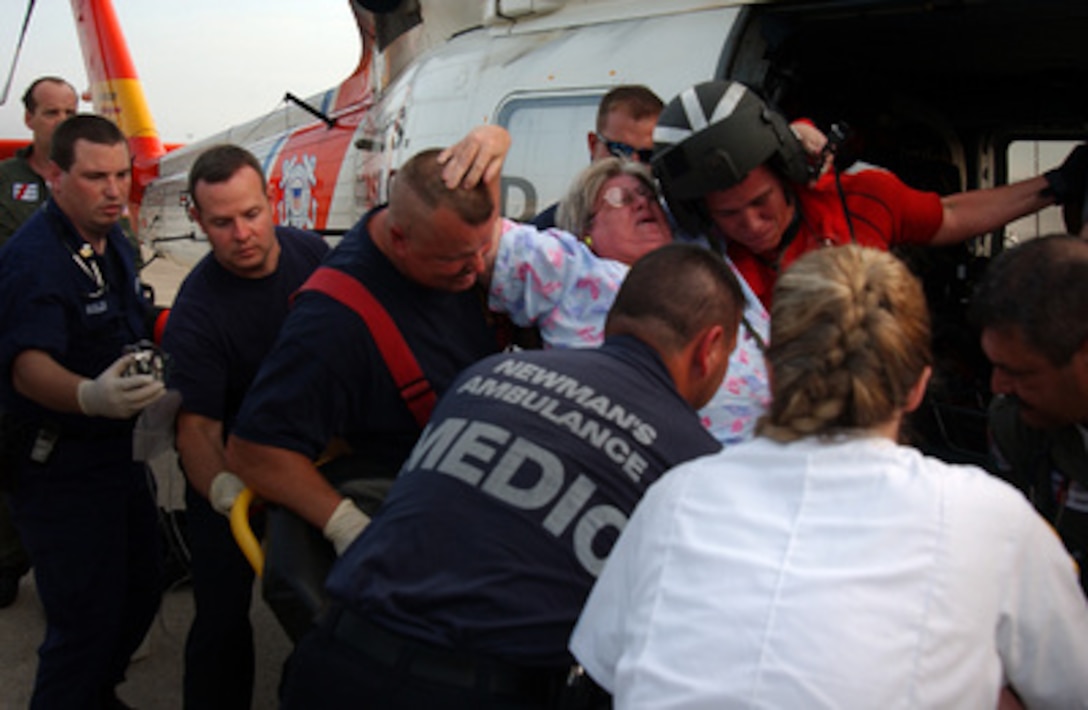A U.S. Coast Guard helicopter rescue crew and paramedics assist a woman onto a gurney at the Coast Guard base in Mobile, Ala., on Sept. 1, 2005. Critically ill patients from a National Guard field hospital in Biloxi, Miss., are being transported to the Coast Guard base and transferred to local emergency medical services. 