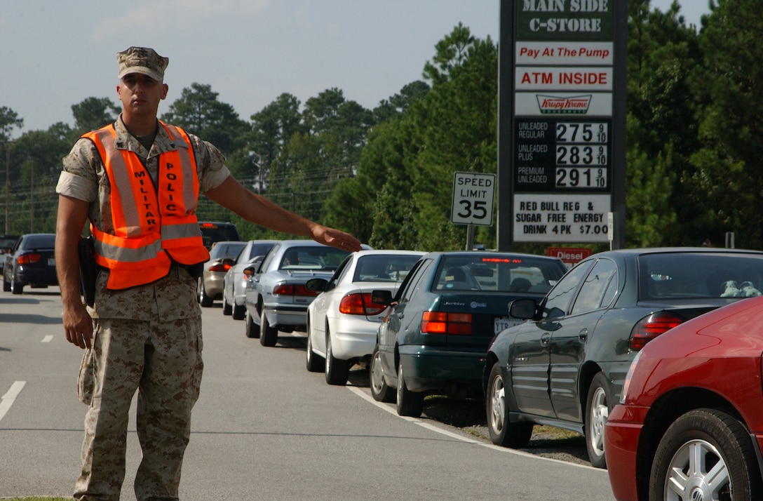 MARINE CORPS BASE CAMP LEJEUNE, N.C. - Cpl. Charles Lambert, a military policeman with MP Company, Headquarters and Support Battalion, MCB, directs traffic while motorist swarm base gas stations to fill up before gas prices rise. With gas prices rising so are thefts as people try and steal gas rather than trying to find other means of transportation than driving. (Official U.S. Marine Corps photo by Lance Cpl. Drew Barker)