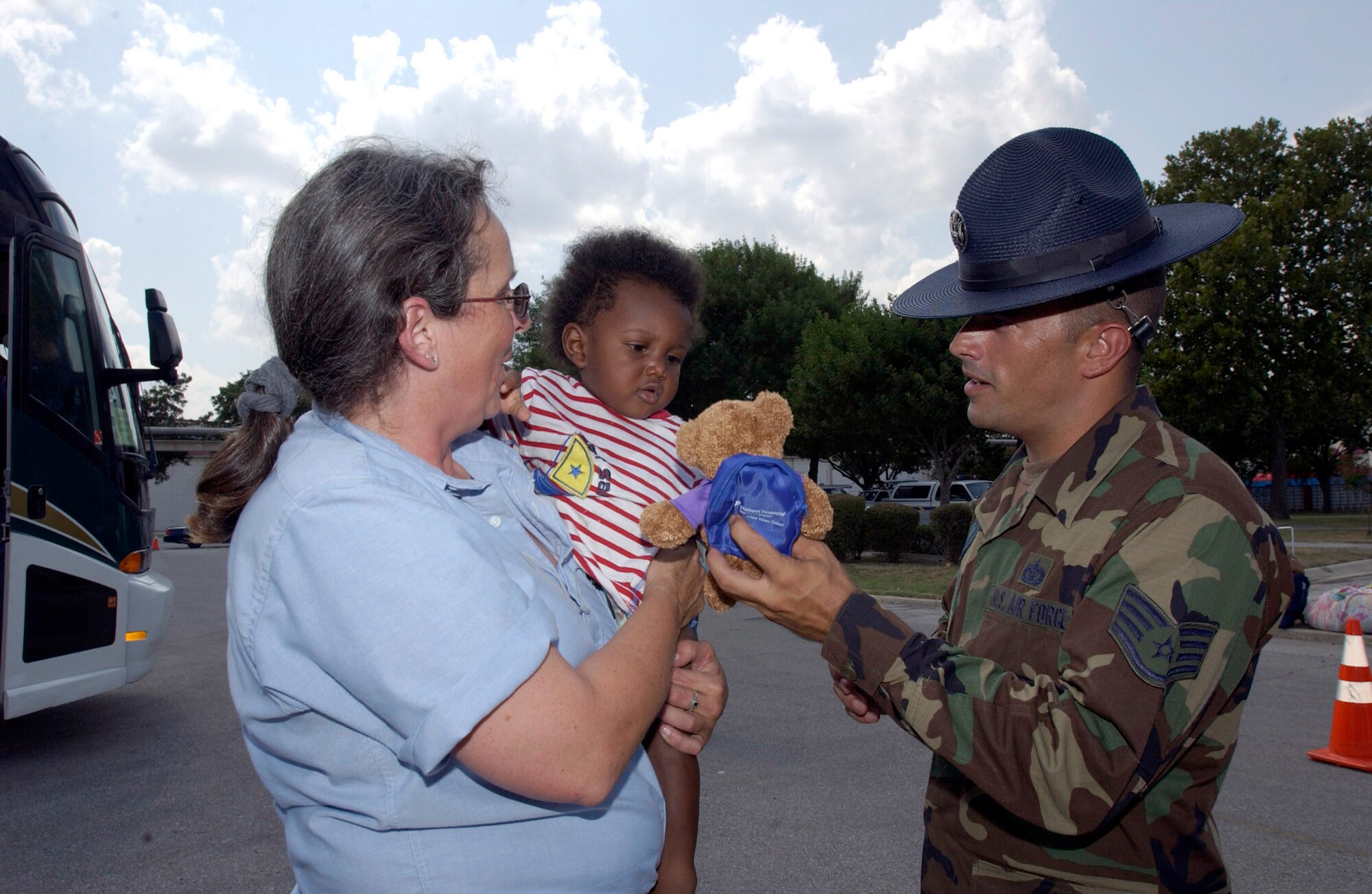 SAN ANTONIO -- Staff Sgt. Chris Clark, gives tiny evacuee Antonio Michaels a stuffed animal as he arrived here.  The evacuees arrived Sept. 2 from New Orleans. They are being inprocessed, given a medical checkup, fed and put into temporary shelters. Sergeant Clark is a technical instructor with the 737th Training Squadron at nearby Lackland Air Force Base, Texas.  (U.S. Air Force photo by Tech. Sgt. Mark Borosch)