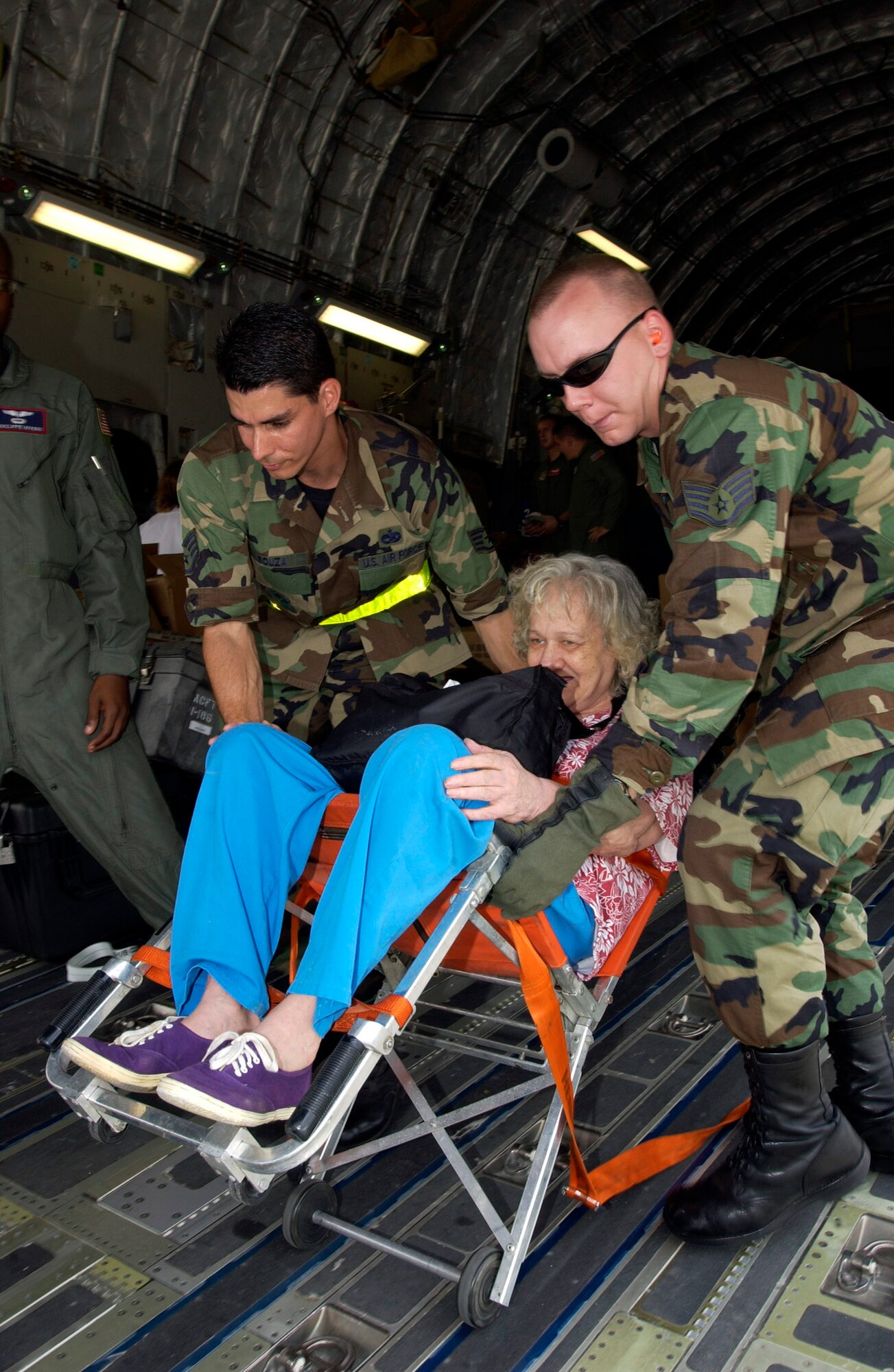 LACKLAND AIR FORCE BASE, Texas -- Staff Sgt. John Souza (left) and Staff Sgt. Michael Vonahmen (right), help Hurricane Katrina evacuees get off a C-17 Globemaster III here.  The evacuees arrived Sept. 2 from New Orleans. They are being inprocessed, given a medical checkup, fed and put into temporary shelters.  The Airmen are assigned to the 343rd Training Squadron.  (U.S. Air Force photo by Tech. Sgt. Mark Borosch)