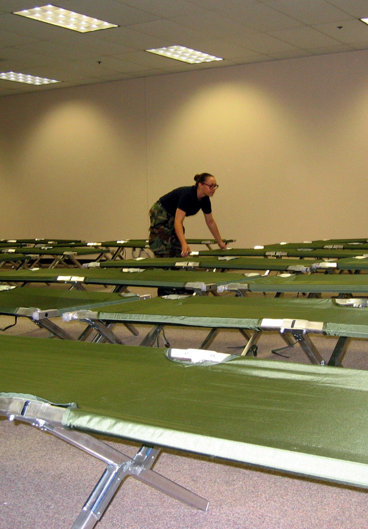 SAN ANTONIO -- Airman Diane Burton aligns cots at a center to house people displaced by Hurricane Katrina. In all, 200 Airmen from nearby Lackland Air Force Base helped tear down modular office furniture in a 350,000 square foot building and set up the cots. Airman Burton is assigned to the 323rd Training Squadron.  (U.S. Air Force photo by Tech. Sgt. J.C. Woodring)