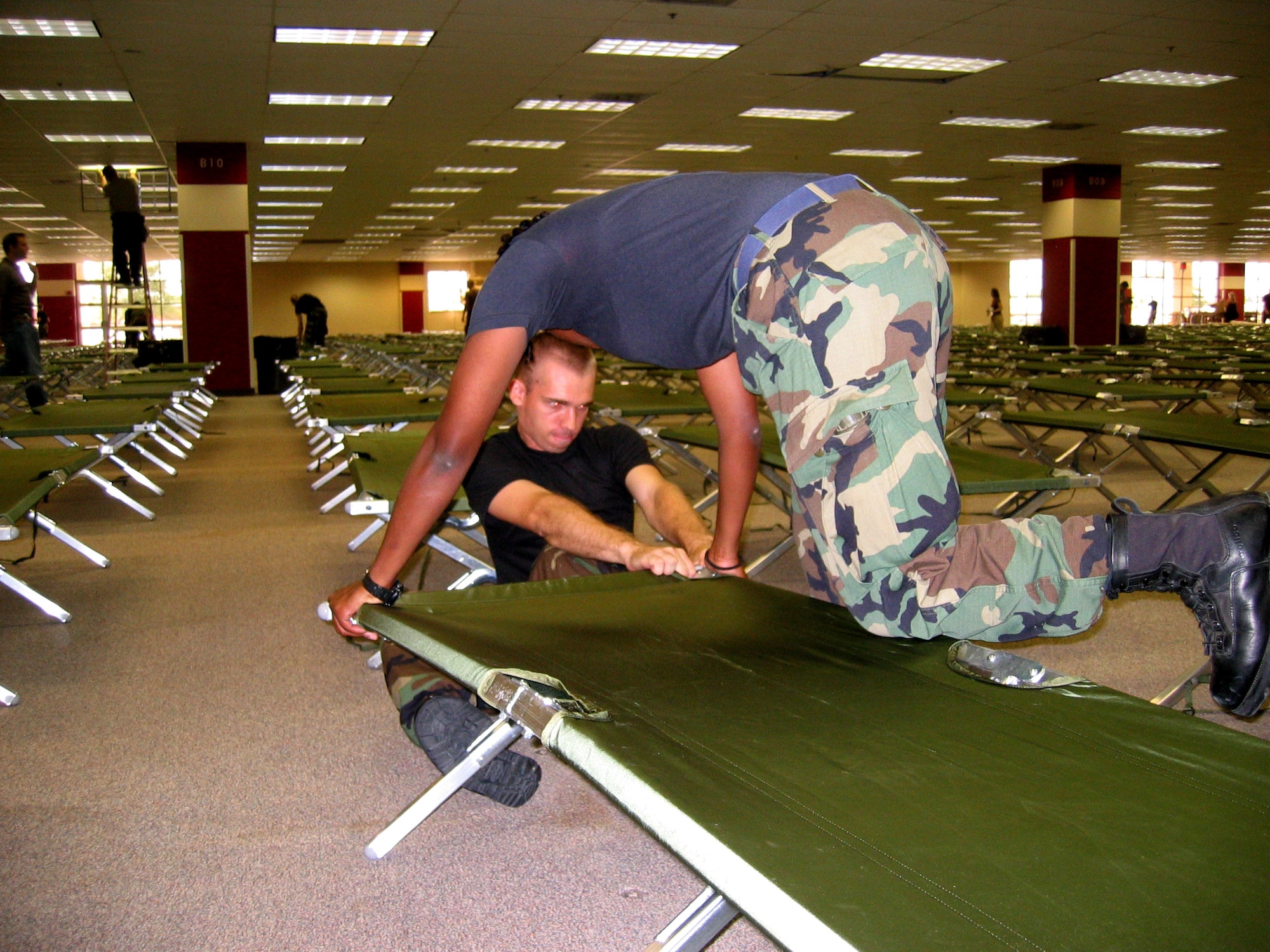 SAN ANTONIO -- Airman Yohanna Tucker helps Airman 1st Class Daniel Morton put one of about 2,500 cots together at a center to house people displaced by Hurricane Katrina. In all, 200 Airmen from nearby Lackland Air Force Base helped tear down modular office furniture in a 350,000 square foot building and set up the cots. Airman Tucker is assigned to the 331st Training Squadron, and Airman Morton is assigned to the 323rd TRS.  (U.S. Air Force photo by Tech. Sgt. J.C. Woodring)