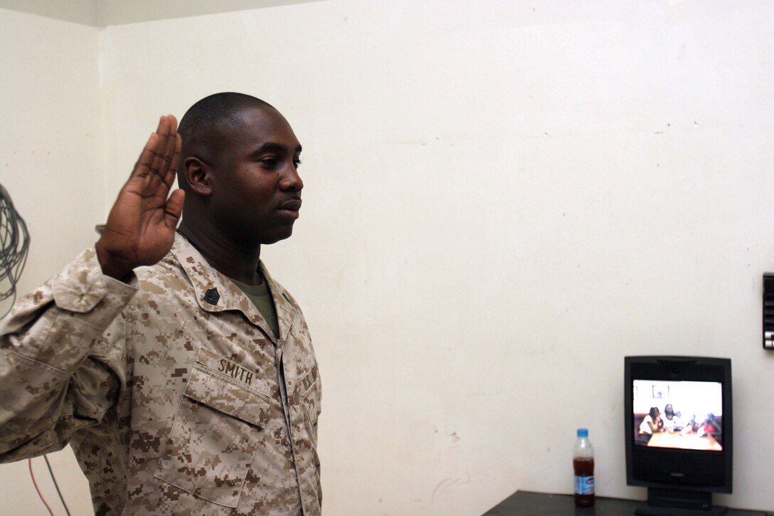 AL ASAD, Iraq ? Gunnery Sgt. Ron S. Smith, the MALS-26 aviation information systems chief, takes the oath of enlistment during a reenlistment ceremony at the Marine Air Group 26 headquarters building, at Al Asad, Iraq.  Smith?s family was able to sit in on the ceremony because of video teleconferencing technology.