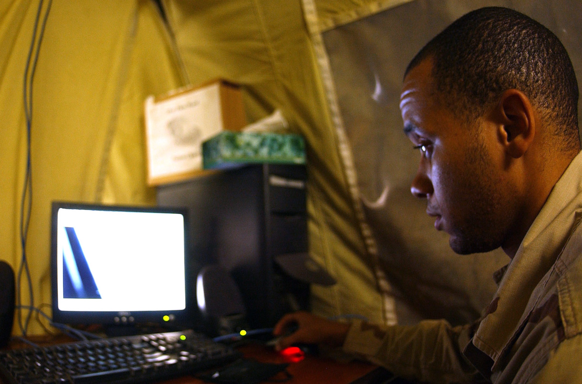 BALAD AIR BASE, Iraq -- Staff Sgt. Fred Mathis looks at pictures of the damage Hurricane Katrina caused at his home station, Keesler Air Force Base, Miss., from his computer at work.  Sergeant Mathis has a pregnant wife and 3-year-old daughter at Keesler.  He is an aeromedical clerk with the contingency aeromedical staging facility here.  (U.S. Air Force photo by Senior Airman Tim Beckham)