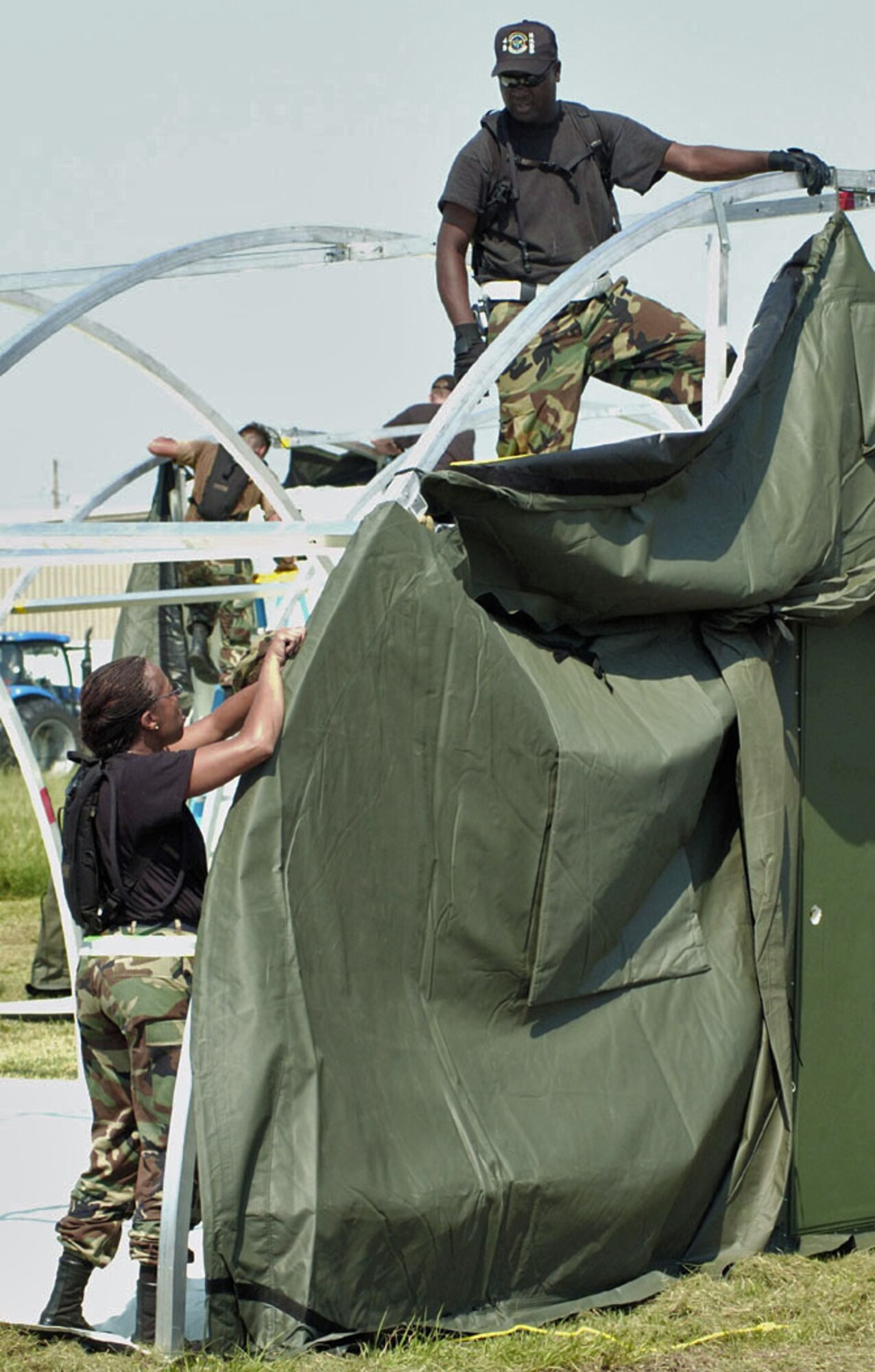 NEW ORLEANS -- Tech. Sgt. Lenore Cobb (left) and Master Sgt. Tony Wells erect a tent at Louis Armstrong International Airport here Sept. 4.  The tents were flown in from the 49th Materiel Maintenance Group at Holloman Air Force Base, N.M., to house workers supporting the Hurricane Katrina relief effort.  (U.S. Air Force photo by Master Sgt. Jack Braden)
