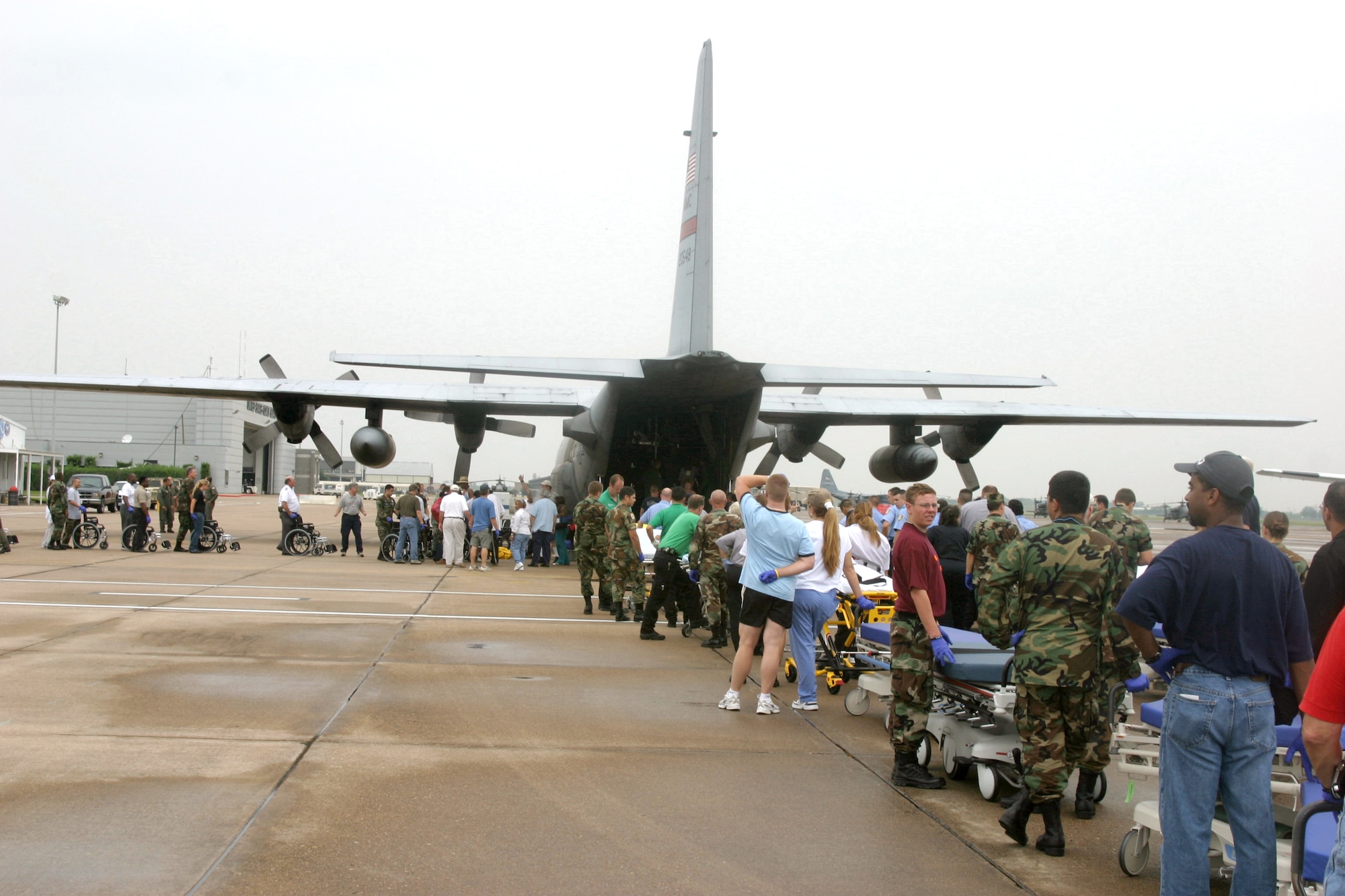 ELLINGTON FIELD, Texas -- Emergency responders here line up to help unload injured evacuees Sept. 3.  C-130 Hercules crews from the 50th Airlift Squadron at Little Rock Air Force Base, Ark., teamed up with Airmen from the 452nd Aeromedical Evacuation Squadron at March Air Reserve Base, Calif., to relocate sick and injured patients devastated after Hurricane Katrina.  (U.S. Air Force photo by 1st Lt. Jon Quinlan)