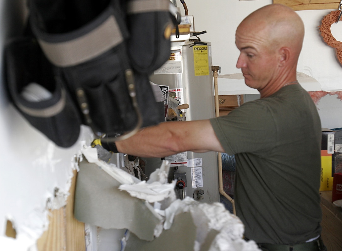 First Sgt. James F. Cully, first sergeant, A Company, 1st Battalion, 8th Marines, cuts through the drywall of Staff Sgt. Edward J. Schneider's Slidell, La., home. Five Marines from Alpha Co. helped Schneider after storm surge from Hurricane Katrina filled his home with five feet of water. The battalion was the Marine Corps' contribution to Joint Task Force Katrina.