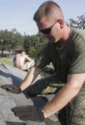 Sgt. Billy Leo, platoon guide, 3rd Platoon, A Company, 1st Battalion, 8th Marines, cuts shingles to fit while patching up Kathleen Faircloth's roof in Mobile, Ala. The Marines made a special trip to Mobile September 10 after hearing Faircloth, the mother of slain Marine Lance Cpl. Bradley Faircloth, had suffered severe damage to her home caused by Hurricane Katrina.