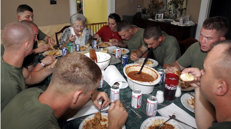 Marines from A Company, 1st Battalion, 8th Marines share a lunch of spaghetti and garlic bread with Helen and Kathleen Faircloth September 10. The grandmother and mother of Lance Cpl. Bradley Faircloth, killed in action in Fallujah Nov. 26, 2004, needed help repairing the damage to the roof caused by Hurricane Katrina, and the Marines responded to assist the family of their fallen comrade.