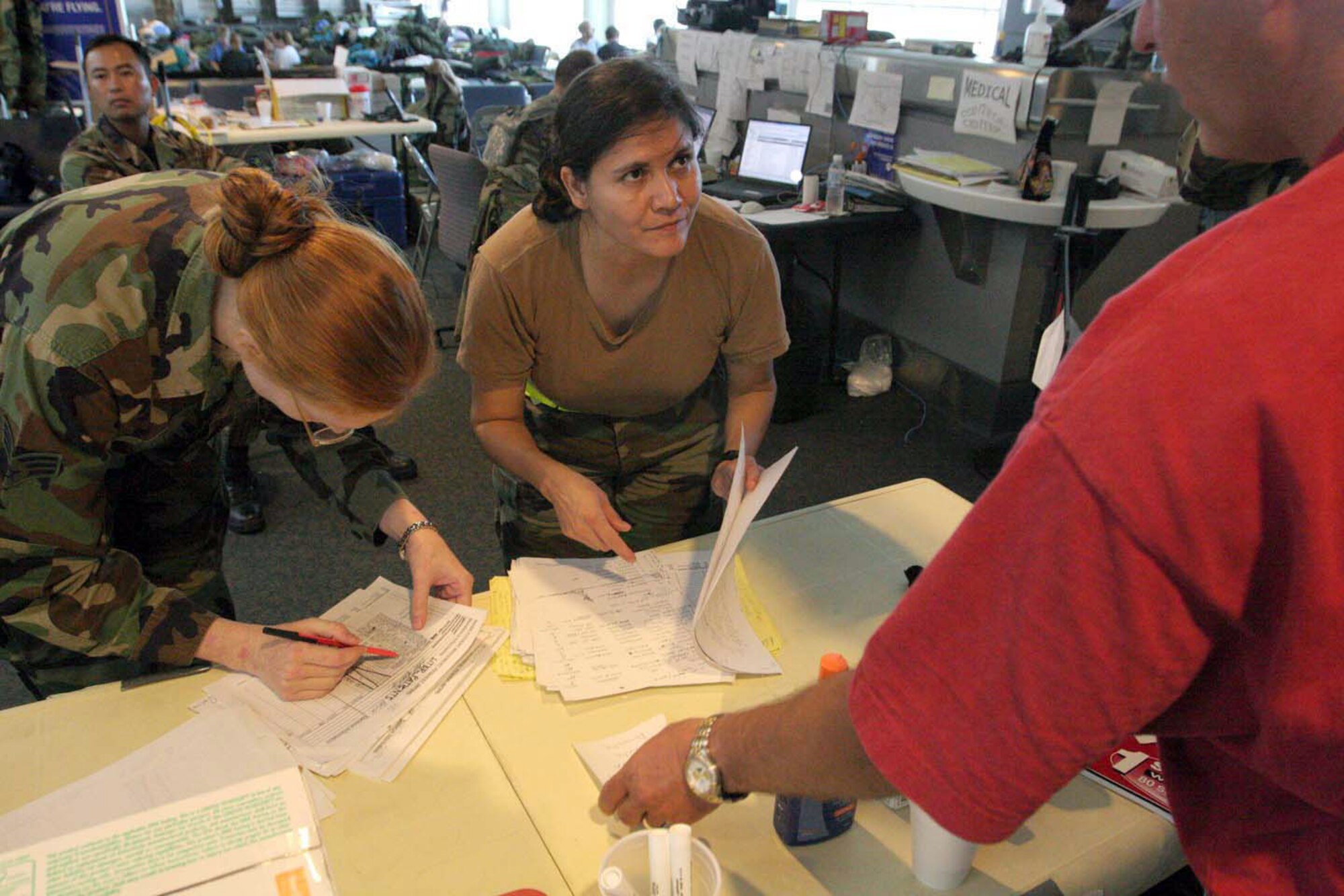 LOUIS ARMSTRONG NEW ORLEANS INTERNATIONAL AIRPORT, La. -- Staff Sgt. Sonia Chavez and her co-worker assist Joel Hunt in his search for his mother, Miriam.  The 375th Medical Group is deployed here from Scott Air Force Base, Ill., to assist in airlifting and providing medical care to displaced Americans affected by Hurricane Katrina. Sergeant Chavez searched through passenger manifests trying to find Mr. Hunt's mother. Mrs. Hunt was later located in a nursing home facility in northern Louisiana. (U.S. Air Force photo by Robert Gallagher)