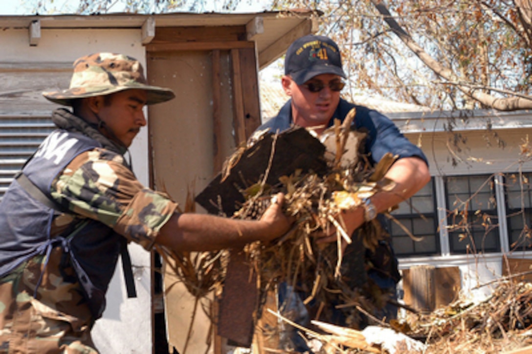 Sailors from the Mexican Navy and U.S. Navy work together to clear debris from a house in Biloxi, Miss., on Sept. 11, 2005. The Mexican Navy is assisting the U.S. Navy in providing humanitarian assistance to victims of Hurricane Katrina. Department of Defense units are mobilized as part of Joint Task Force Katrina to support the Federal Emergency Management Agency's disaster relief efforts in the Gulf Coast areas devastated by Hurricane Katrina. 