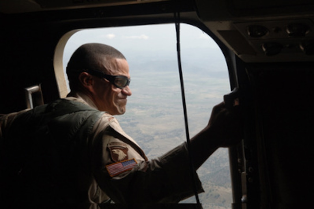 U.S. Army Lt. Col. Neil Higgins leans out the hatch to watch for the drop zone during a leaflet drop over Forward Operating Base Salerno, Afghanistan, on Sept. 8, 2005. Higgins is attached to Combined/Joint Task Force 76. 