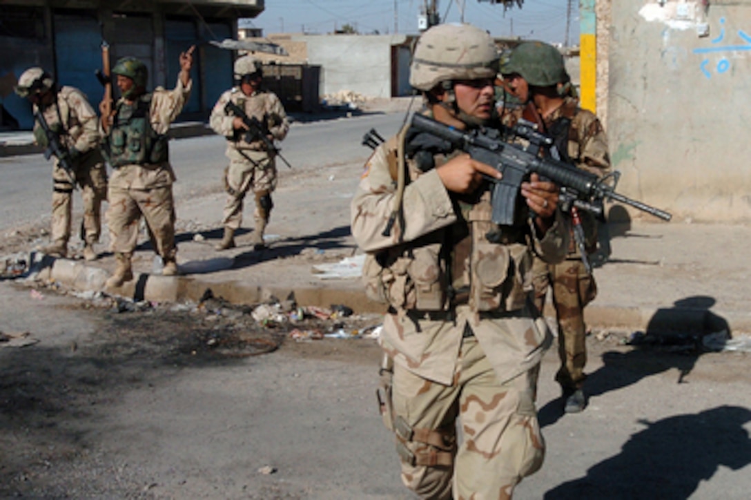 U.S. Army and Iraqi soldiers cross an intersection during a routine security patrol in downtown Tal Afar, Iraq, on Sept. 11, 2005. Iraqi army security forces, with assistance from the 3rd Armored Cavalry Regiment, are providing security for the region of Tal Afar in order to disrupt insurgent safe havens and to clear weapons cache sights in the area of operation. 
